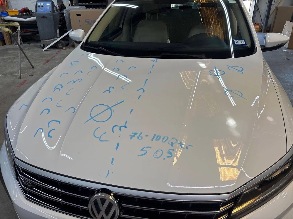 White VW Passat hood with hail dents marked during a written dent-count estimate at DG Collision Center Lewisville TX